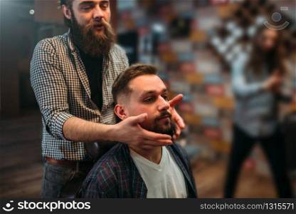 Barber shows his work to the client man. Hairdressing salon interior on background