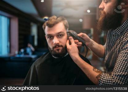 Barber trimming hair of the client man by clipper. Barbershop concept