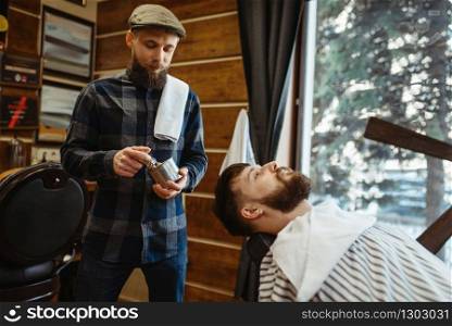 Barber with brush and bearded customer, beard cutting. Professional barbershop is a trendy occupation. Male hairdresser and client in hair salon. Barber with brush and customer, beard cutting