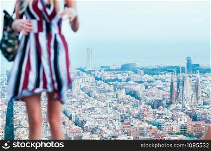 Barcelona, Catalonia, Spain. Blurred pretty girl, against city view, enjoys sunset on top of Old Bunker hill. Sagrada Familia, port and harbor. Travel concept. Film Grain effect