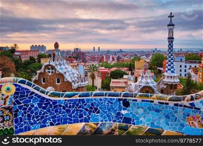 Barcelona city view from Guell Park with colorful mosaic buildings in tourist attraction Park Guell in the morning on sunrise. Barcelona, Spain. Barcelona city view from Guell Park. Sunrise view of colorful mosaic building in Park Guell