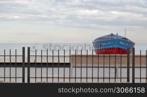BARCELONA - MAY 25, 2012: The train is passing by in front of the boat on the beach.