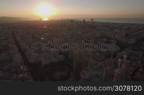 BARCELONA, SPAIN - JULY 27, 2016: Aerial cityscape of Barcelona at sunset. View to the houses and unfinished church Sagrada Familia. Famous landmark is under construction since 1882