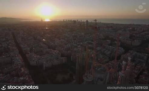 BARCELONA, SPAIN - JULY 27, 2016: Aerial cityscape of Barcelona at sunset. View to the houses and unfinished church Sagrada Familia. Famous landmark is under construction since 1882