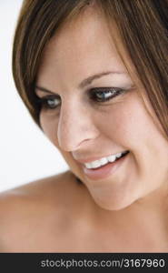 Bare Caucasian mid adult brunette woman looking to side and smiling.