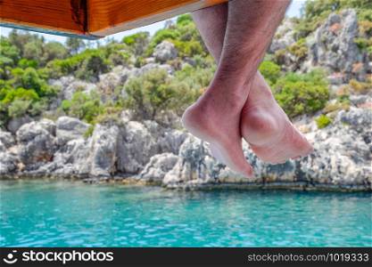 Bare feet hanging from a wooden pier over sea water. Holiday vacation by the sea.. Bare feet hanging from wooden pier over sea water. Holiday vacation by the sea.