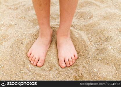 Bare feet of a young child in the sand