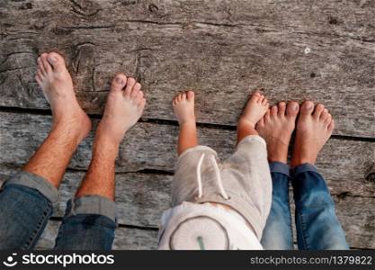 Bare feet of family. Wooden bridge. Mom, dad and baby walk bare feet on the wooden bridge. Happy young family spending time together. The concept of family holiday. copy space. selective focus.. Bare feet of family. Wooden bridge. Mom, dad and baby walk bare feet on the wooden bridge. Happy young family spending time together. The concept of family holiday. copy space. selective focus