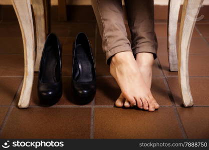 Bare female feet under the white vintage retro table. Tired businesswoman woman girl with leg cramps relaxing no high heels.