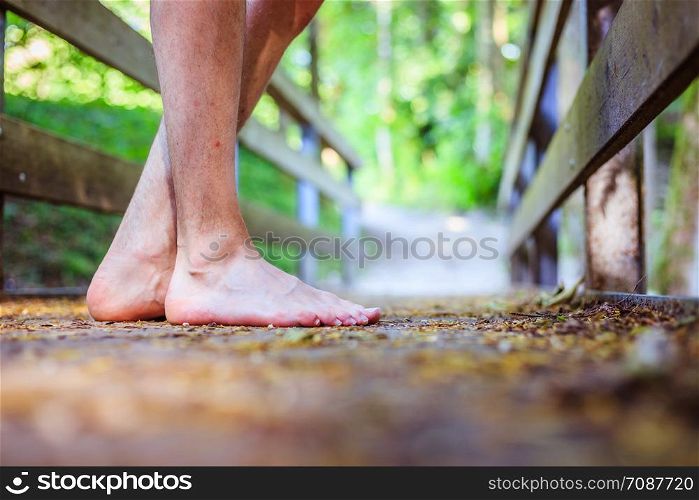 Barefoot feet on a rusty old wooden bridge in the forest, adventure