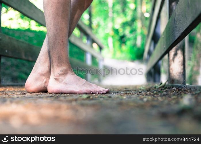 Barefoot feet on a rusty old wooden bridge in the forest, adventure