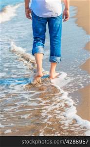 barefoot man in jeans walking on the sea shore