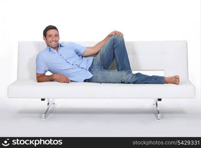 Barefoot man lying on a couch