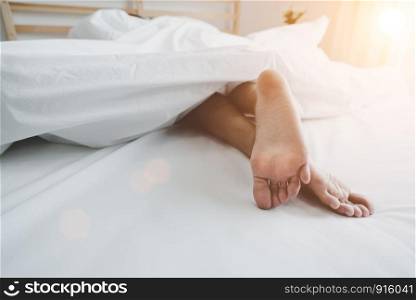 Barefoot of human on bed in morning. Single and Working people concept. Lazy day and Happiness home theme.