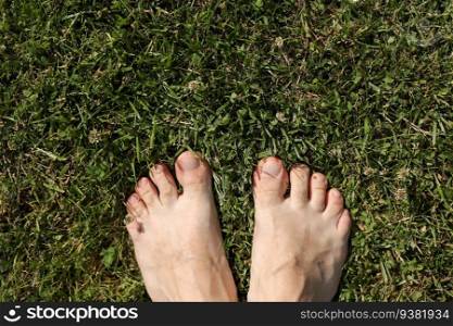 Barefoot on fresh bright green grass on hot day. Male feet stand on lawn outdoors. Freedom, summer relax concept. Earth Day. Earthing or grounded yoga. Rustic lifestyle. Top view. Barefoot on fresh bright green grass on hot day. Male feet stand on lawn outdoors. Freedom, summer relax concept. Earth Day. Earthing or grounded yoga. Rustic lifestyle. Top view.