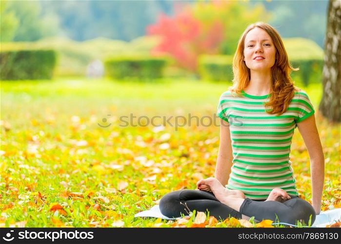 barefoot red-haired girl practicing yoga in the autumn park