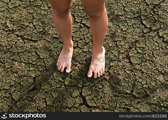 Barefoot woman standing on a drought land