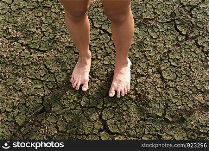 Barefoot woman standing on a drought land