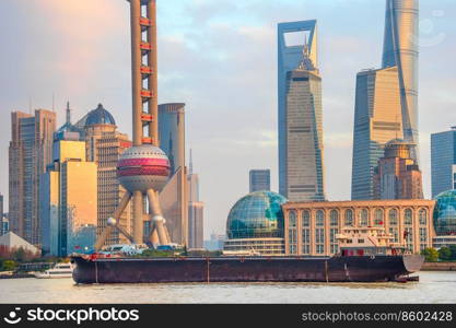 Barge by sunset Shanghai skyline with famous tv tower and skyscrapers of modern architecture, China