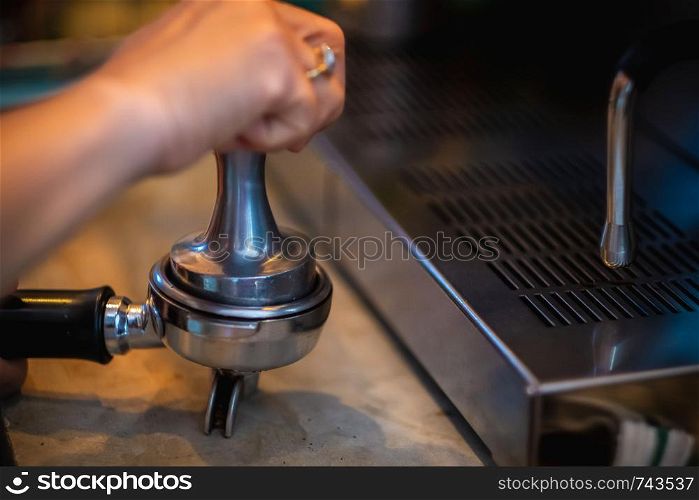 Barista hand making coffee from the machine,Presses ground coffee using tamper.