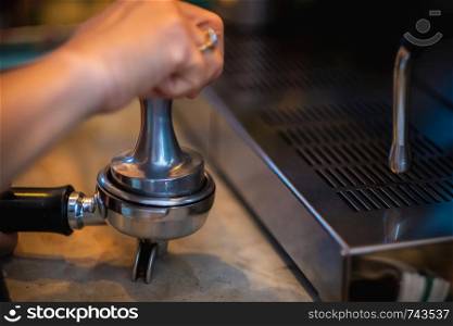 Barista hand making coffee from the machine,Presses ground coffee using tamper.