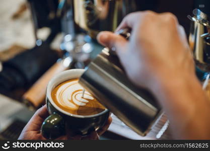 barista making latte art, shot focus in cup of milk and coffee, vintage filter image