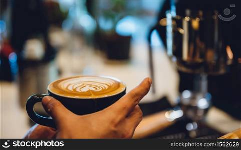 barista making latte art, shot focus in cup of milk and coffee, vintage filter image