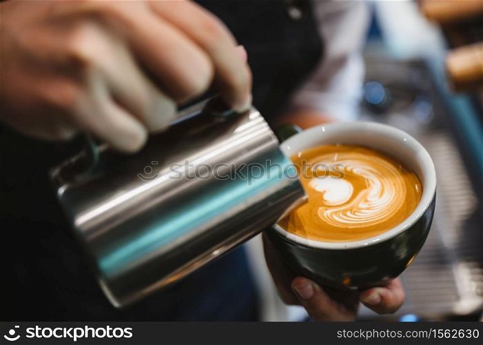 barista making latte art, shot focus in cup of milk and coffee, vintage filter image