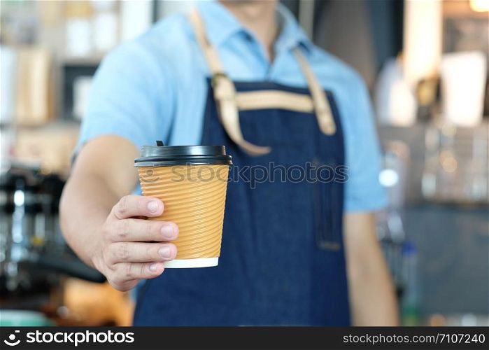Barista man hand holding a coffee cup at cafe counter background, small business owner, food and drink industry