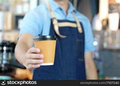 Barista man hand holding a coffee cup at cafe counter background, small business owner, food and drink industry