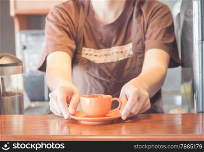 Barista offering mini orange cup of coffee, stock photo