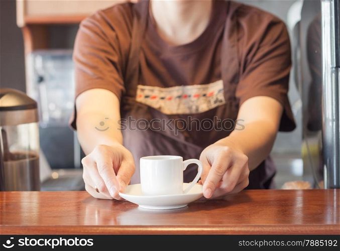 Barista offering mini white cup of coffee, stock photo