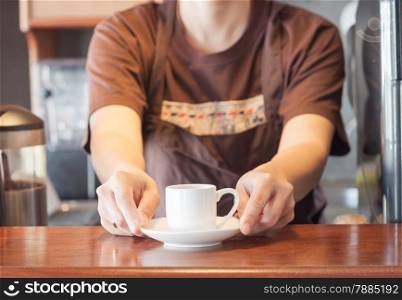 Barista offering mini white cup of coffee, stock photo