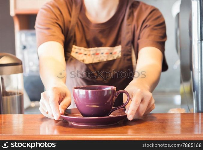 Barista offering purple cup of coffee, stock photo