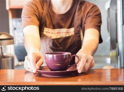 Barista offering purple cup of coffee, stock photo