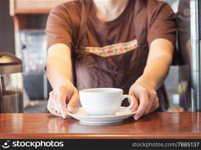 Barista offering white cup of coffee, stock photo