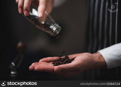 barista pouring coffee powder from a coffee grinder to a dripper to make fresh coffee in the cafe.