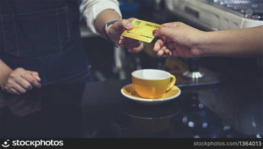 Barista serving customer and Woman is paying for coffee by credit card in coffee shop