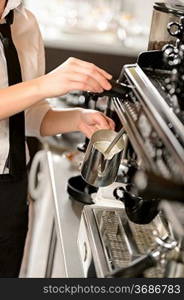 Barista steaming milk for hot cappuccino with machine