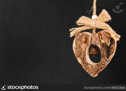 Bark wooden heart on a rope with little opaque brass bell in the middle