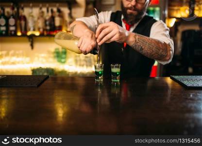 Barkeeper pouring alcoholic beverage in glass behind restaurant bar counter. Barkeeper pouring alcoholic beverage in glass