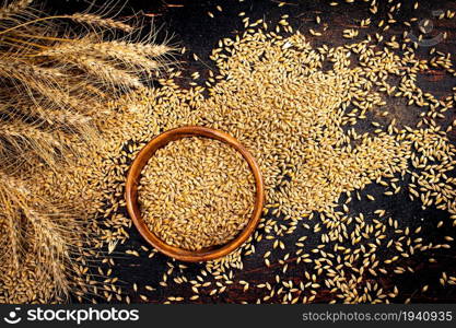 Barley grains in a wooden bowl. Top view. On a dark background. . Barley grains in a wooden bowl. Top view.