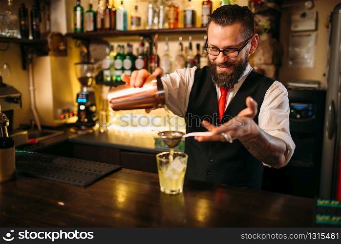 Barman flaring behind bar counter. Restaurant shelves with alcoholic drinks bottles on background. Barman flaring behind bar counter