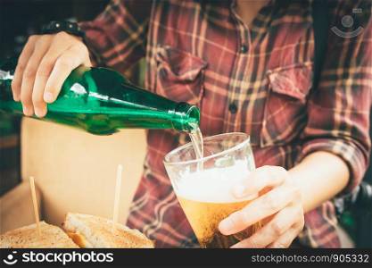Barman holding bottle beer and pouring in mug.
