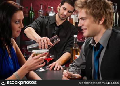 Barman making cocktail for young couple at the bar