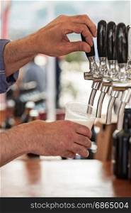 Barman pouring a fresh beer in a glass. Pouring fresh beer