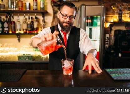 Barman pouring alcoholic drink in glass. Bartender flairing in restaurant