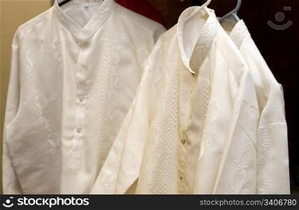 Barongs hangs ready for the groomsmen to put on at a formal asian style wedding ceremony.