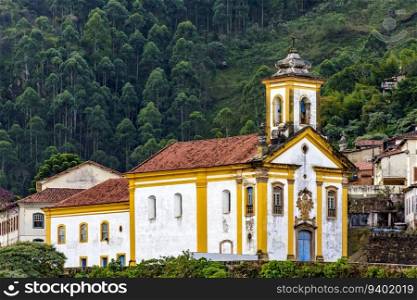Baroque church and houses in front of the forest in the historic city of Ouro Preto in Minas Gerais. Baroque church and houses in front of the forest