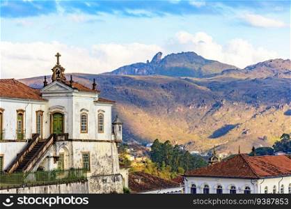 Baroque church and mountains in the city of Ouro Preto in Minas Gerais with the mountains and peak of Itacolomi in the background during sunset. Baroque church and mountains in the city of Ouro Preto